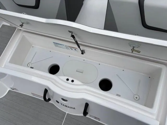 Slide: The Image of 2023 Yamaha Boats AR220 storage compartment with open lid, showcasing interior design and features. - 30