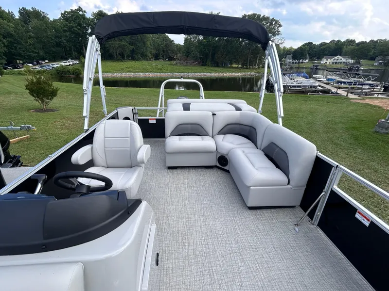 Slide: The Image of 2024 Landau Island Breeze 232 Cruise pontoon boat with spacious seating and canopy on a grassy lakeside. - 5