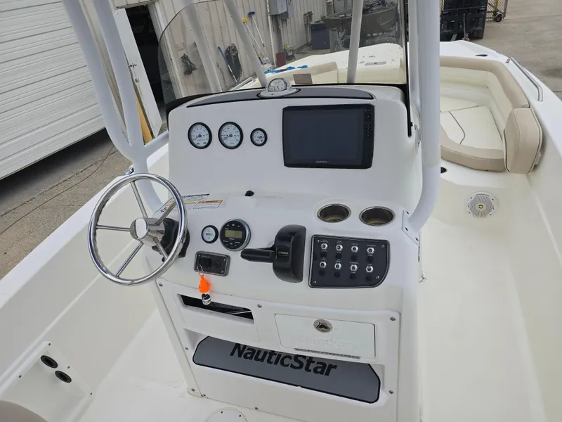 Slide: The Image of 2017 NauticStar 231 Coastal boat dashboard with steering wheel and navigation controls. - 10