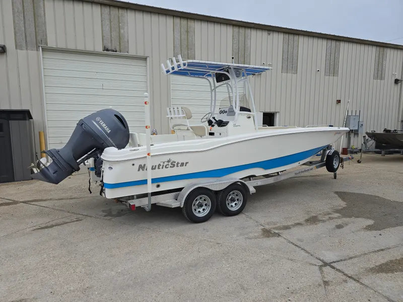 Slide: The Image of 2017 NauticStar 231 Coastal boat on trailer, parked outside industrial building. - 2