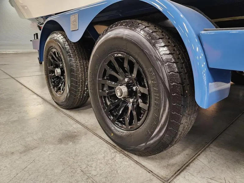 Slide: The Image of Blue Axis T235 trailer with black wheels, 2025 model, on concrete floor. - 26