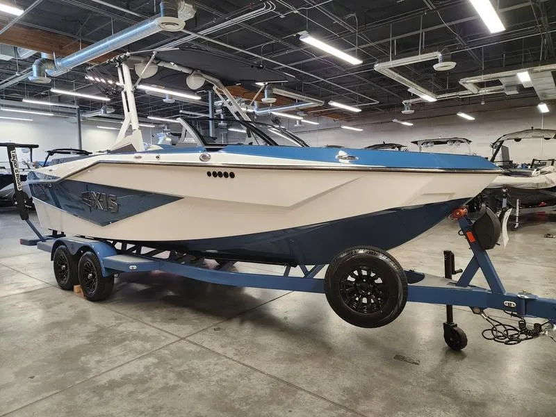 Slide: The Image of 2025 Axis T235 boat on trailer in showroom, blue and white design. - 7
