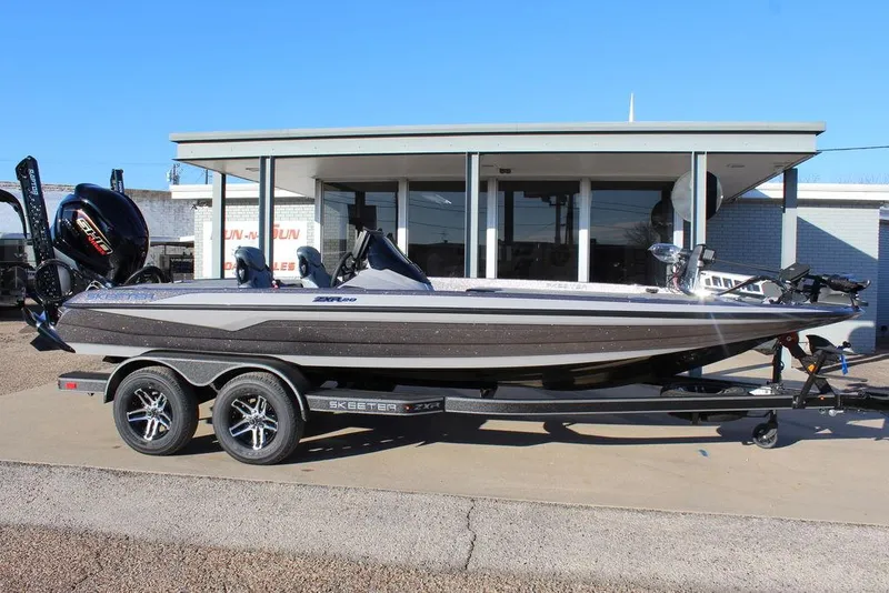 Slide: The Image of 2025 Skeeter ZXR20 boat on trailer, parked outside a building. - 2