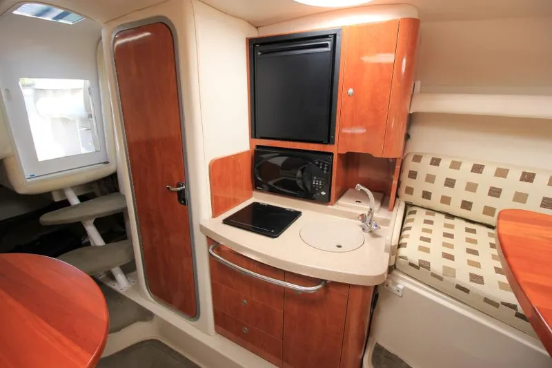 Slide: The Image of 2004 Four Winns 288 Vista cabin interior with kitchenette, featuring wood cabinetry and seating area. - 21