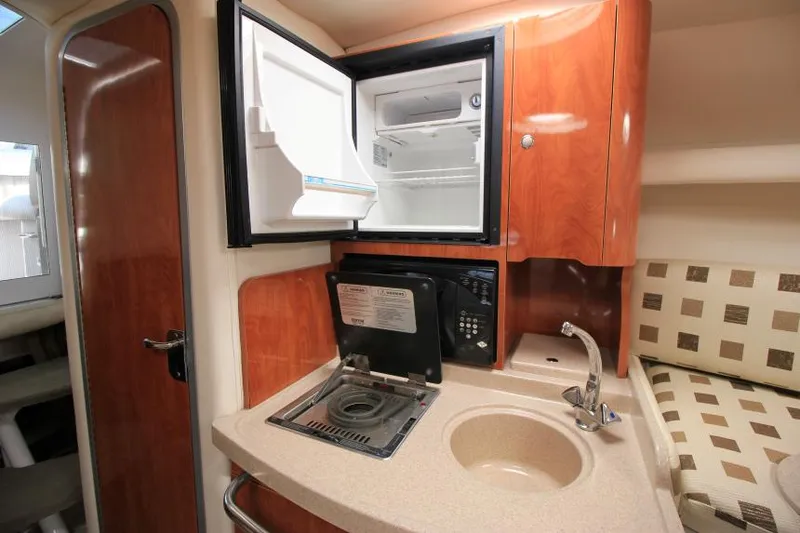 Slide: The Image of 2004 Four Winns 288 Vista boat interior with kitchenette, featuring a sink, stove, and mini-fridge. - 22