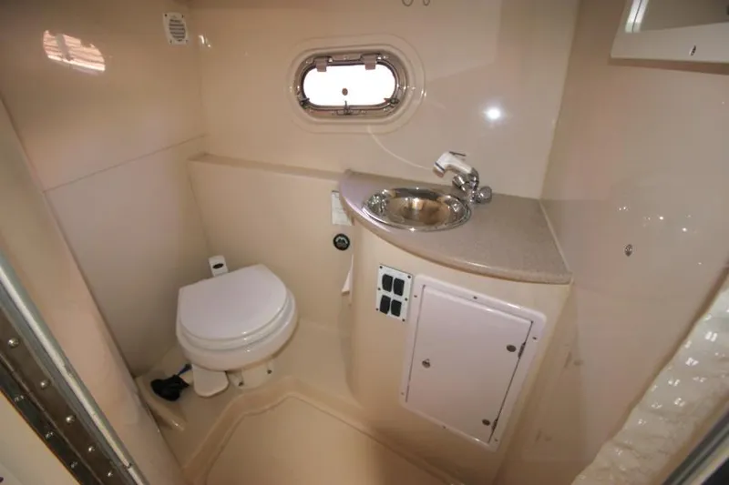 Slide: The Image of 2004 Four Winns 288 Vista boat bathroom with toilet, sink, and porthole window. - 26