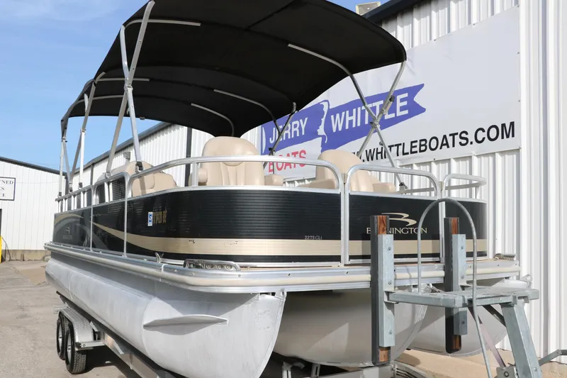 Slide: The Image of 2010 Bennington 2275 GLI pontoon boat on trailer, black canopy, parked at dealership. - 10
