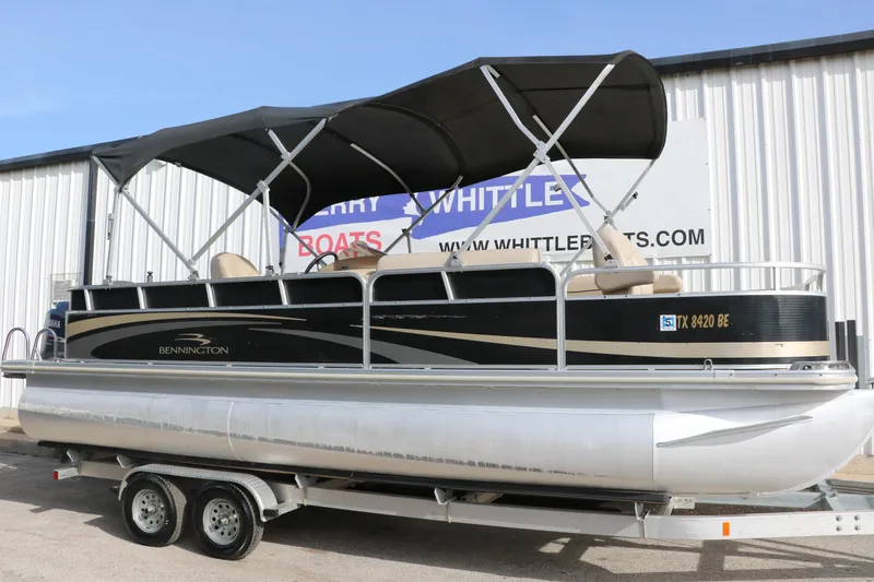 Slide: The Image of 2010 Bennington 2275 GLI pontoon boat on trailer, black canopy, parked outside. - 13