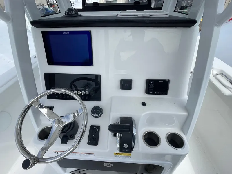 Slide: The Image of 2025 Sea Pro 242 Center Console boat dashboard with steering wheel and electronic controls. - 11