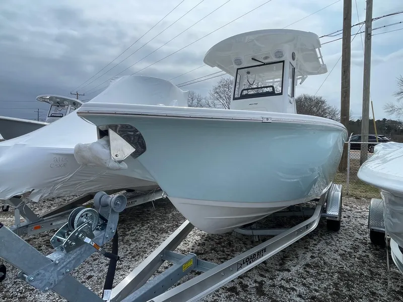 Slide: The Image of 2025 Sea Pro 242 Center Console boat on trailer, light blue hull, overcast sky. - 2