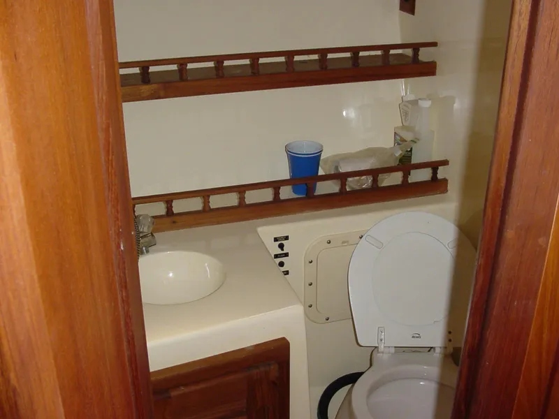 Slide: The Image of 1996 Albemarle 275 Express boat bathroom with sink, toilet, and wooden shelves. - 23