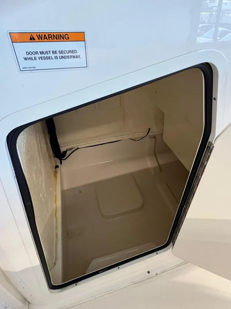 Slide: The Image of 2022 Bayliner Trophy T22CC storage compartment with warning label for secure door closure. - 13