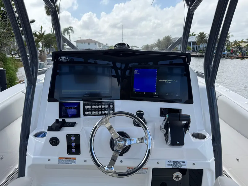 Slide: The Image of 2023 Sea Fox 328 Commander dashboard with dual screens and steering wheel, docked by a canal. - 15