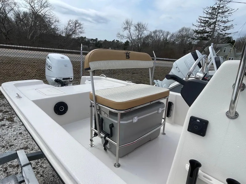 Slide: The Image of 2025 Carolina Skiff E18 JVX CC boat with seating and outboard motor, parked outdoors. - 4