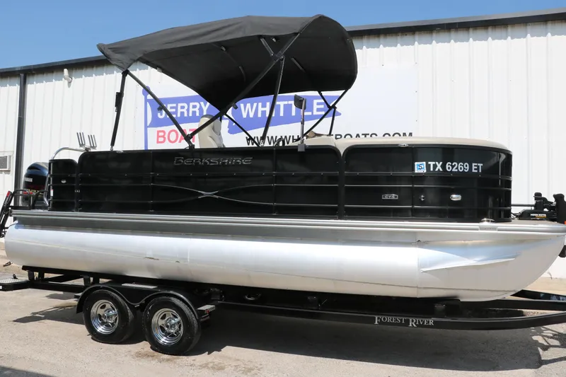 Slide: The Image of 2019 Berkshire 211RFC CTS pontoon boat with canopy on trailer, parked outside a building. - 1