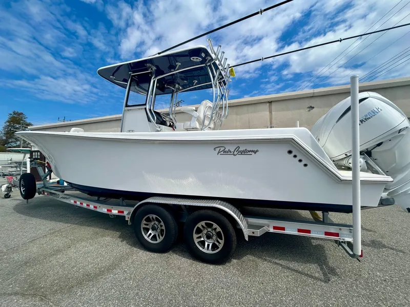 Slide: The Image of 2025 Pair Customs 28 Center Console boat on trailer, side view under blue sky. - 2