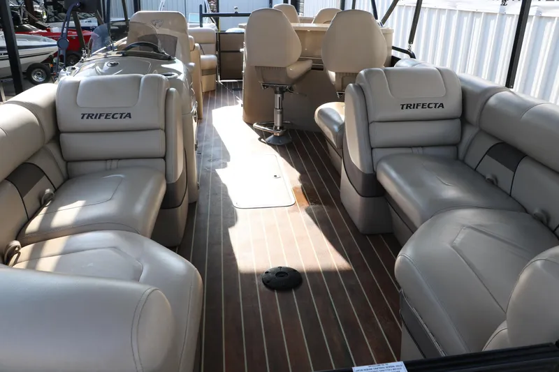 Slide: The Image of 2018 Trifecta 23 RFE pontoon boat interior with beige seating and wood-style flooring. - 18