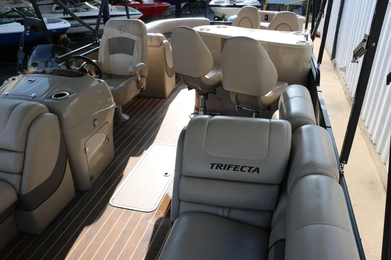 Slide: The Image of 2018 Trifecta 23 RFE pontoon boat interior with beige seating and wood-style flooring. - 19