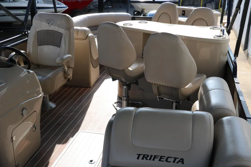 Slide: The Image of 2018 Trifecta 23 RFE pontoon boat interior with beige seating and helm. - 21