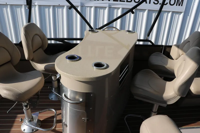 Slide: The Image of 2018 Trifecta 23 RFE boat interior with beige seating and table, featuring cup holders. - 25