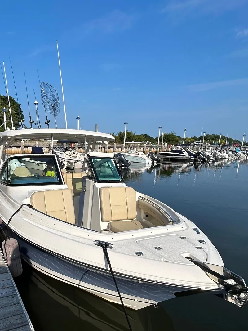 Slide: The Image of 2020 Pursuit DC 235 Dual Console boat docked in a marina under clear blue skies. - 1