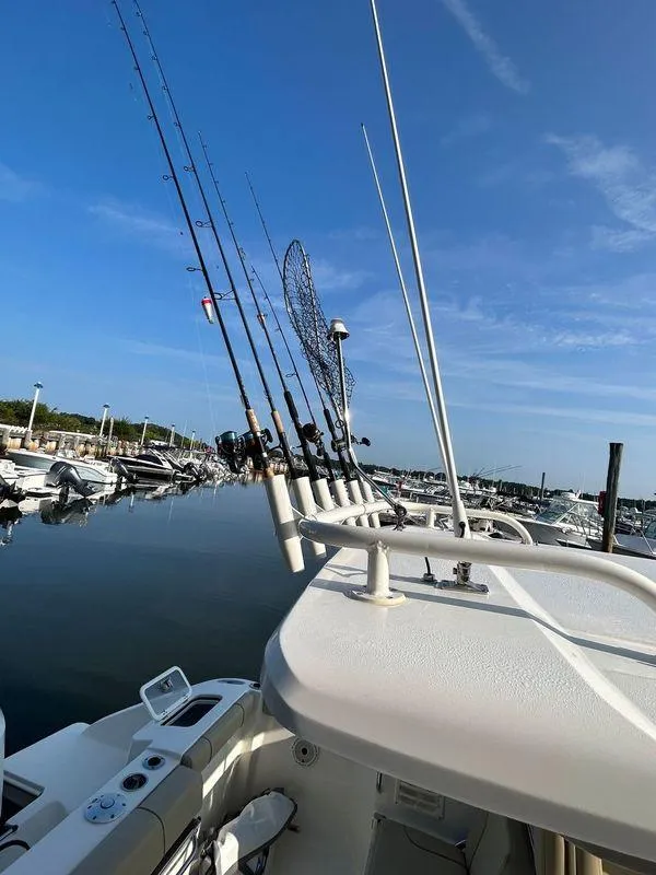 Slide: The Image of 2020 Pursuit DC 235 Dual Console boat with fishing rods docked at marina. - 4