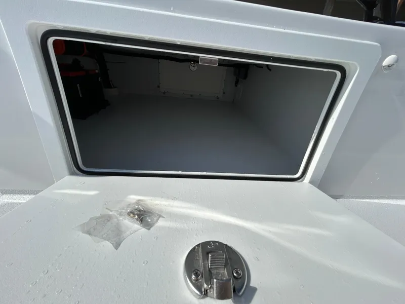 Slide: The Image of Open storage compartment on 2025 Shallow Sport 22 Sport boat, featuring secure latch. - 11