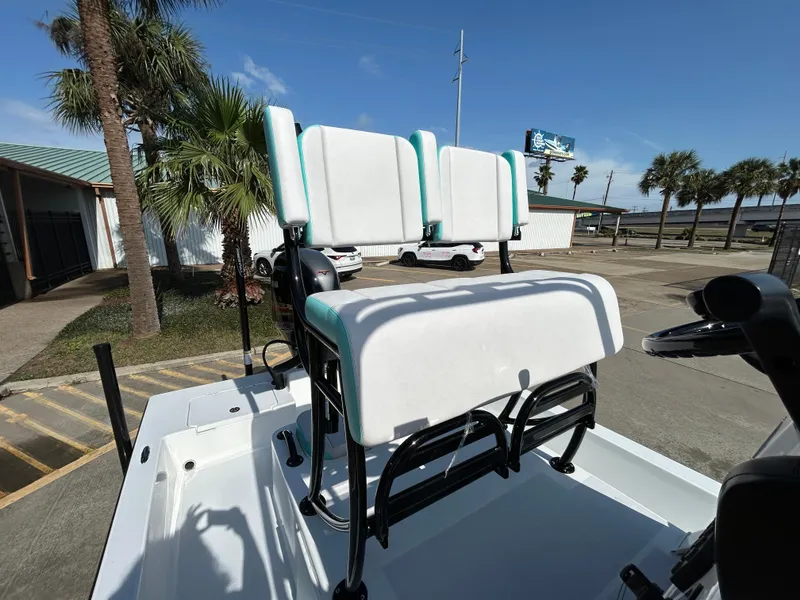Slide: The Image of 2025 Shallow Sport 22 Sport boat with white and teal seating, parked outdoors. - 19