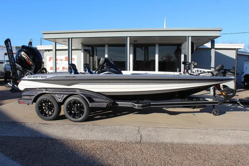 Slide: The Image of 2025 Skeeter FXR20L boat on trailer, parked outside a building. - 2