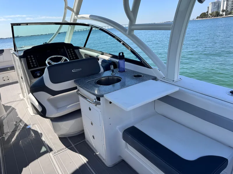 Slide: The Image of 2021 Robalo R317 Dual Console boat interior with helm, seating, and sink by the water. - 28