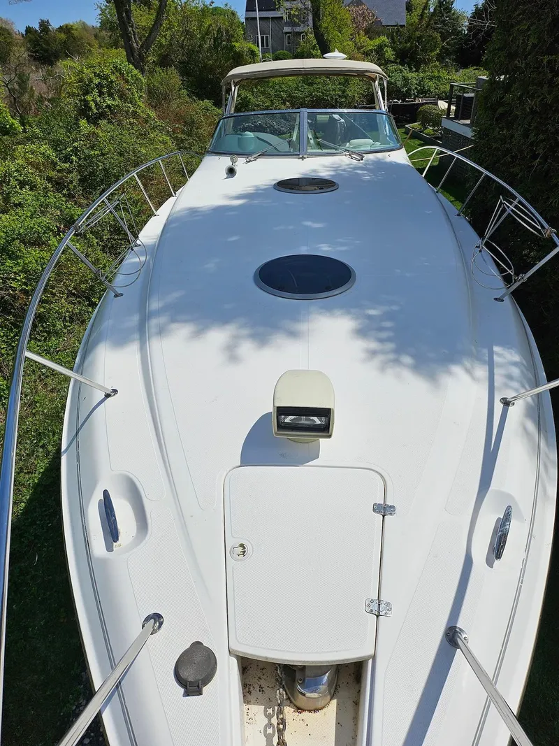 Slide: The Image of 2002 Wellcraft 38 Excalibur boat with sleek white deck and lush greenery background. - 11