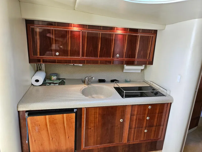 Slide: The Image of 2002 Wellcraft 38 Excalibur boat kitchen with wood cabinets, sink, and mini fridge. - 4