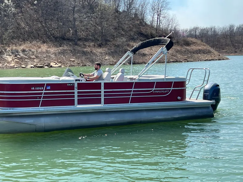 Slide: The Image of 2014 Starcraft SLS3 pontoon boat on a lake with a person steering. - 10