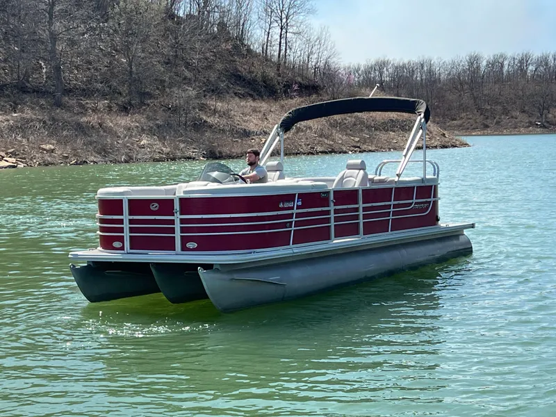 Slide: The Image of 2014 Starcraft SLS3 pontoon boat on a lake with a person steering. - 11
