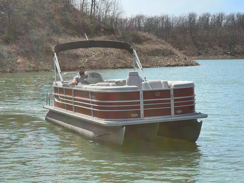 Slide: The Image of 2014 Starcraft SLS3 pontoon boat on a calm lake with wooded shoreline. - 12