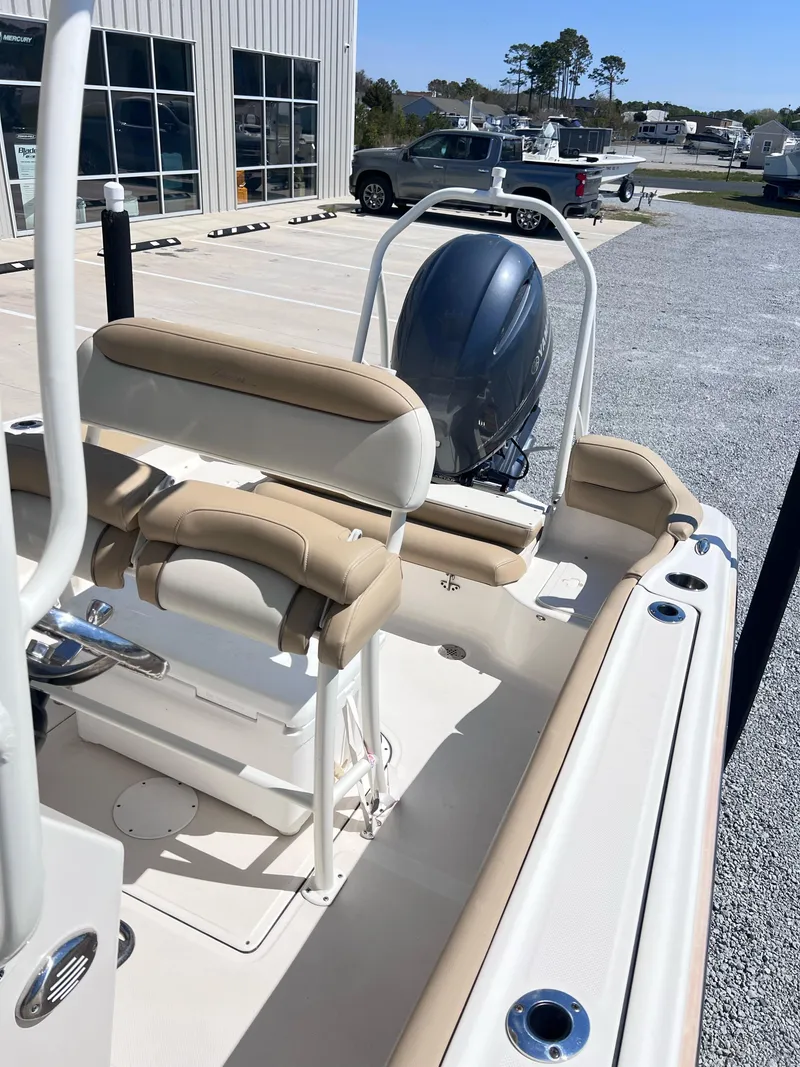 Slide: The Image of 2019 Pioneer 202 Islander boat with beige seating and outboard motor in a parking lot. - 4