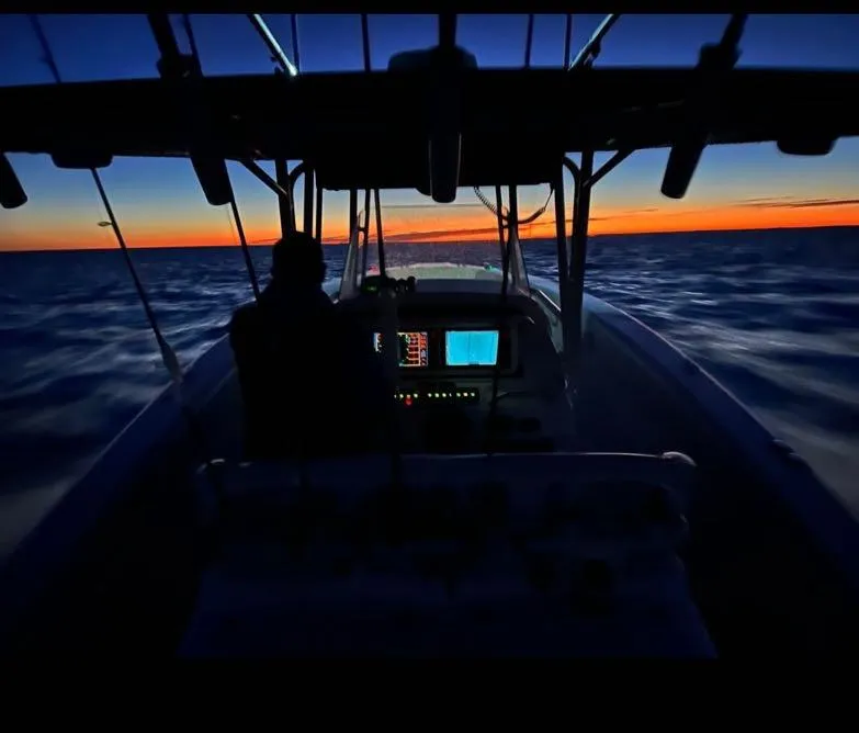 Slide: The Image of Grady-White Bimini 306 boat navigating at sunset, 2000 model, silhouetted against vibrant horizon. - 25