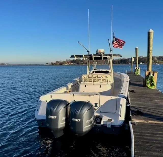 Slide: The Image of Grady-White Bimini 306 boat docked, dual Yamaha engines, American flag, clear blue sky. - 4
