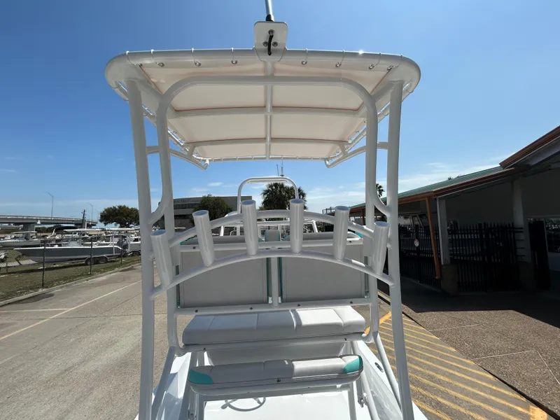 Slide: The Image of 2025 Shallow Sport 24 Sport boat with T-top and rod holders, parked outdoors. - 18