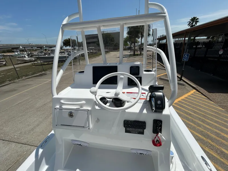 Slide: The Image of 2025 Shallow Sport 24 Sport boat console with steering wheel and controls, docked outdoors. - 8