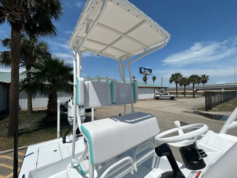 Slide: The Image of 2025 Shallow Sport 24 Sport boat with dual seating and canopy, parked near palm trees. - 9