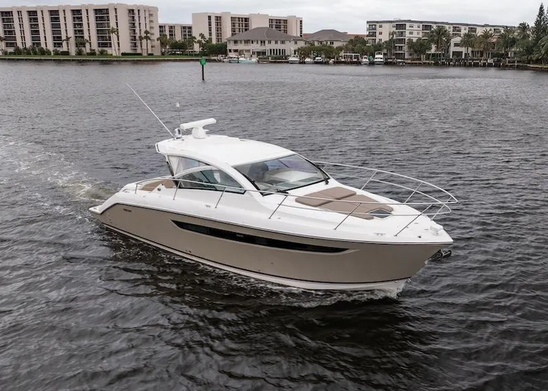 Slide: The Image of 2015 Pursuit SC 365i Sport Coupe cruising on a calm waterway near modern buildings. - 14
