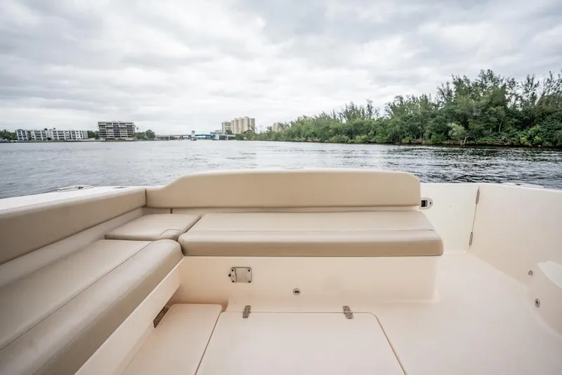 Slide: The Image of 2015 Pursuit SC 365i Sport Coupe boat interior with beige seating, overlooking a serene waterway. - 27