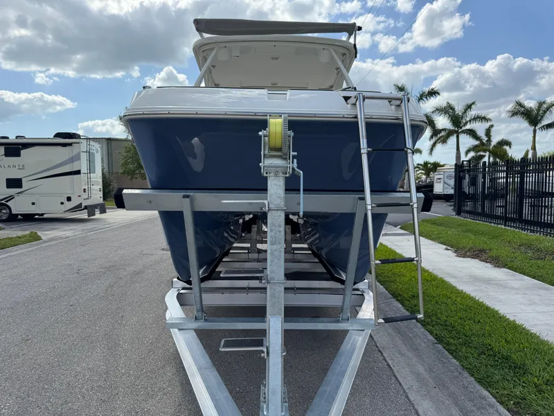 Slide: The Image of 2022 World Cat 230 SD boat on trailer, parked near palm trees and RV. - 13
