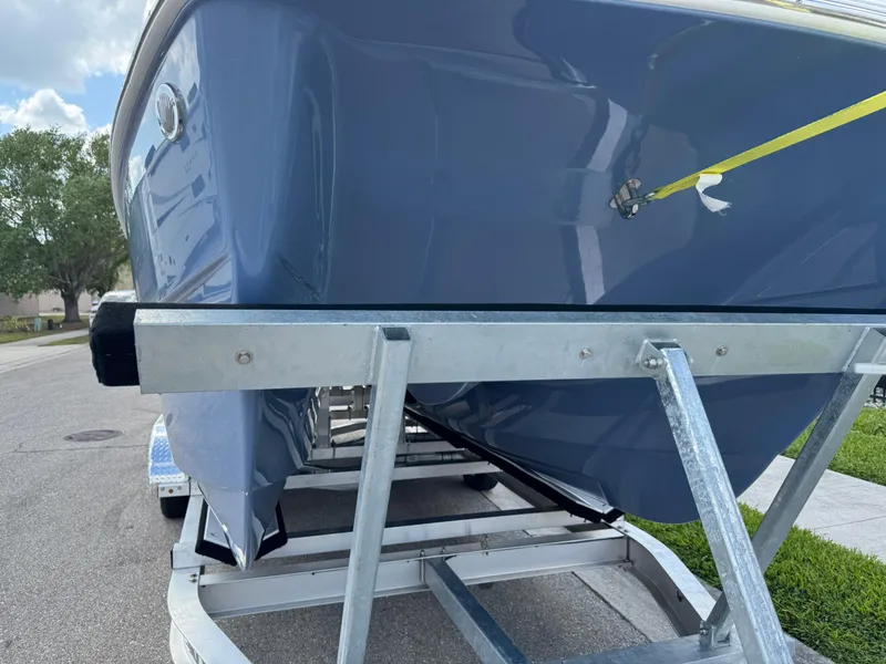 Slide: The Image of 2022 World Cat 230 SD boat on trailer, blue hull, parked on street. - 14