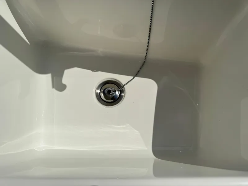 Slide: The Image of Close-up of a clean white sink with a metal drain plug chain. - 35