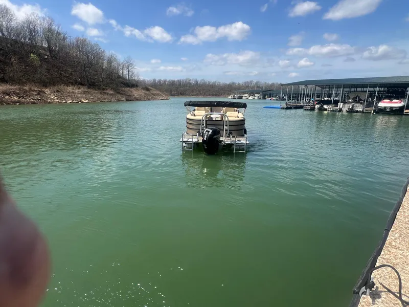 Slide: The Image of 2019 Bentley Pontoons 223 on a serene lake with a marina in the background. - 10