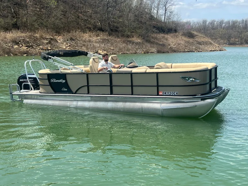 Slide: The Image of 2019 Bentley Pontoons 223 on a serene lake with a person onboard. - 12