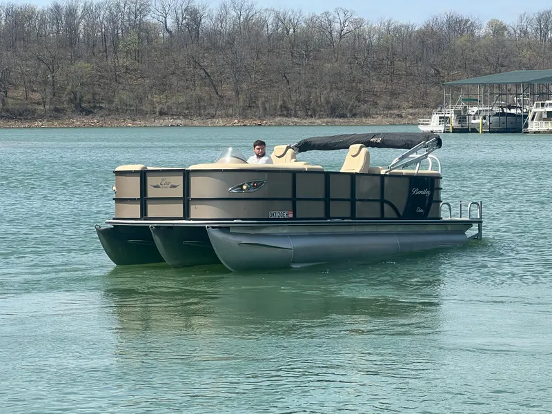 Slide: The Image of 2019 Bentley Pontoons 223 on a calm lake with trees in the background. - 24