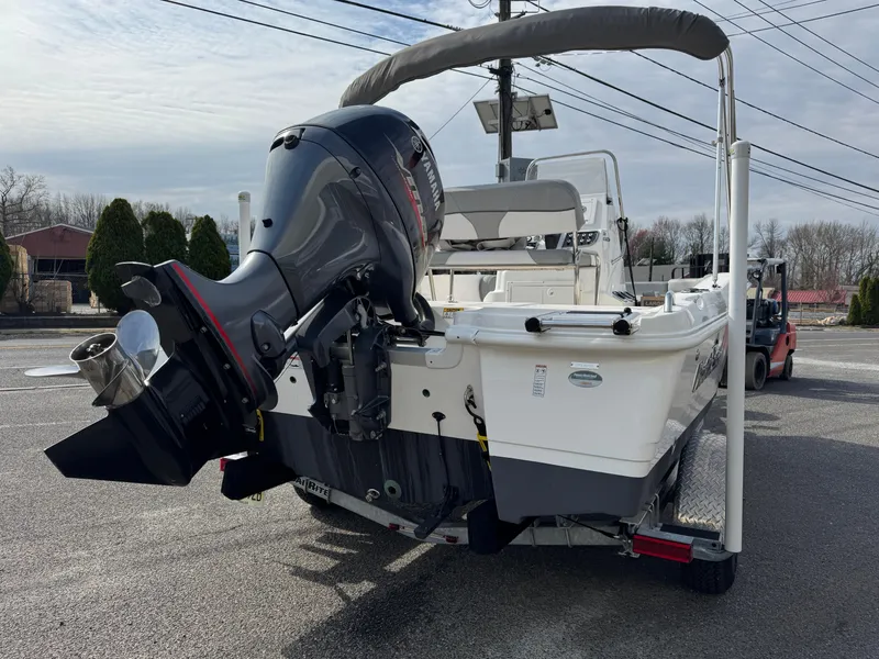 Slide: The Image of 2023 NauticStar 191 Hybrid boat with outboard motor, parked outdoors. - 4